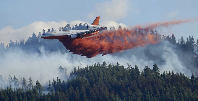FILE - In this Aug. 21, 2015 file photo, a tanker airplane drops fire retardant on a wildfire burning near Twisp, Wash. The state&#039;s commissioner of Public Lands released a proposal Monday, Dec. 2, 2019, that provides some $63 million each year to fight wildfires and take steps to prevent them in the first place. (AP Photo/Ted S. Warren, File)