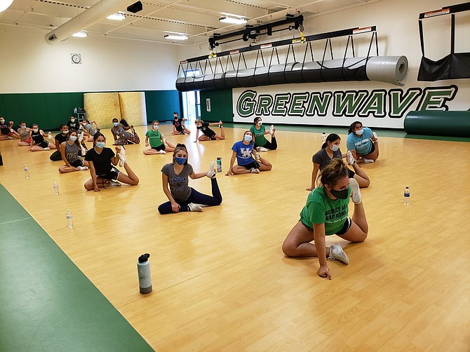 Fallon&#039;s cheerleading squad adjusts to the pandemic guidelines with mask wearing and social distancing during stretches.
