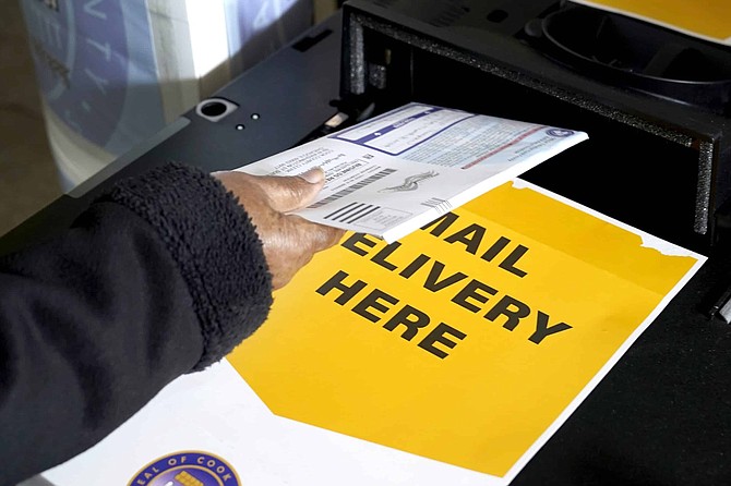 A Cook County, Ill., resident drops off her mail-in ballot Tuesday, Oct. 13, 2020, at a county courthouse in Maywood, Ill. (AP Photo/Charles Rex Arbogast)