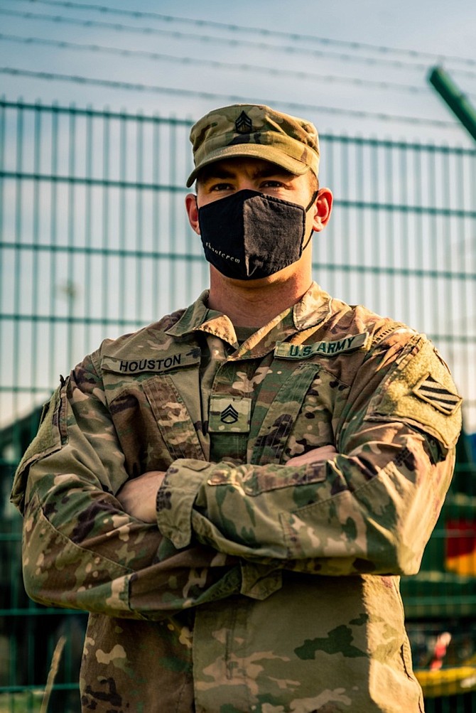 Staff Sgt. Alex Houston stands in front of a motor pool staging area.