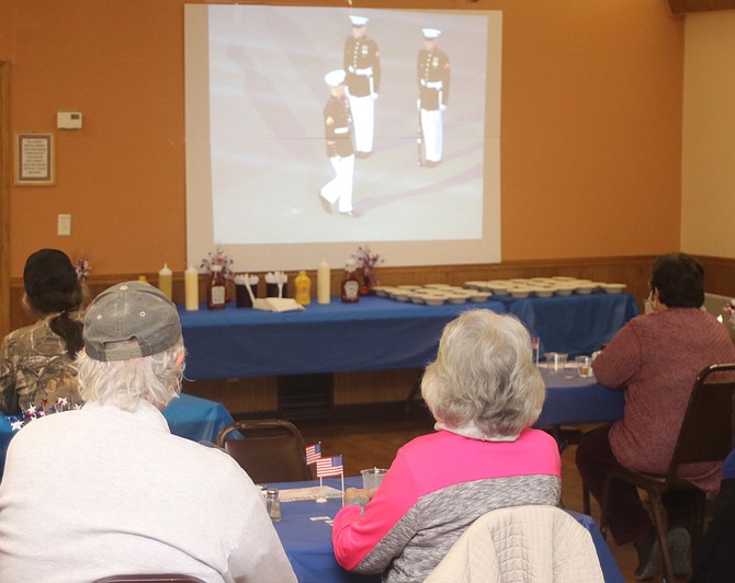 Veterans and guests watch a presentation before dinner is served.
