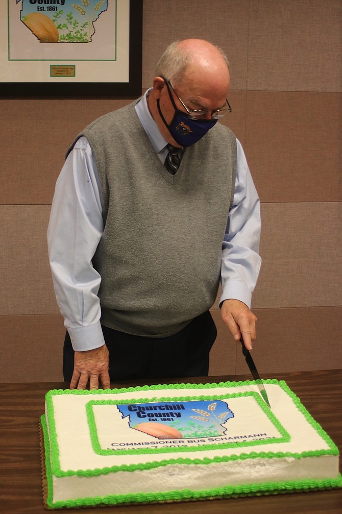 Commissioner Bus Scharmann begins to cut his retirement cake.