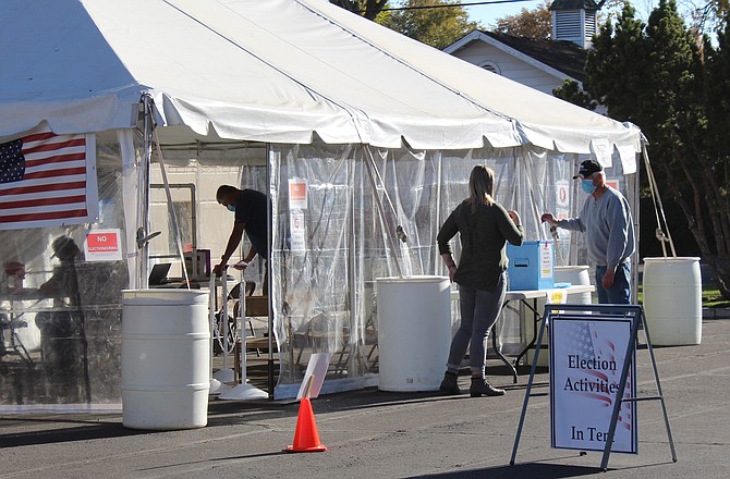 A voter drops off a ballot at the Election Tent behind the Minden Courthouse on Monday afternoon.