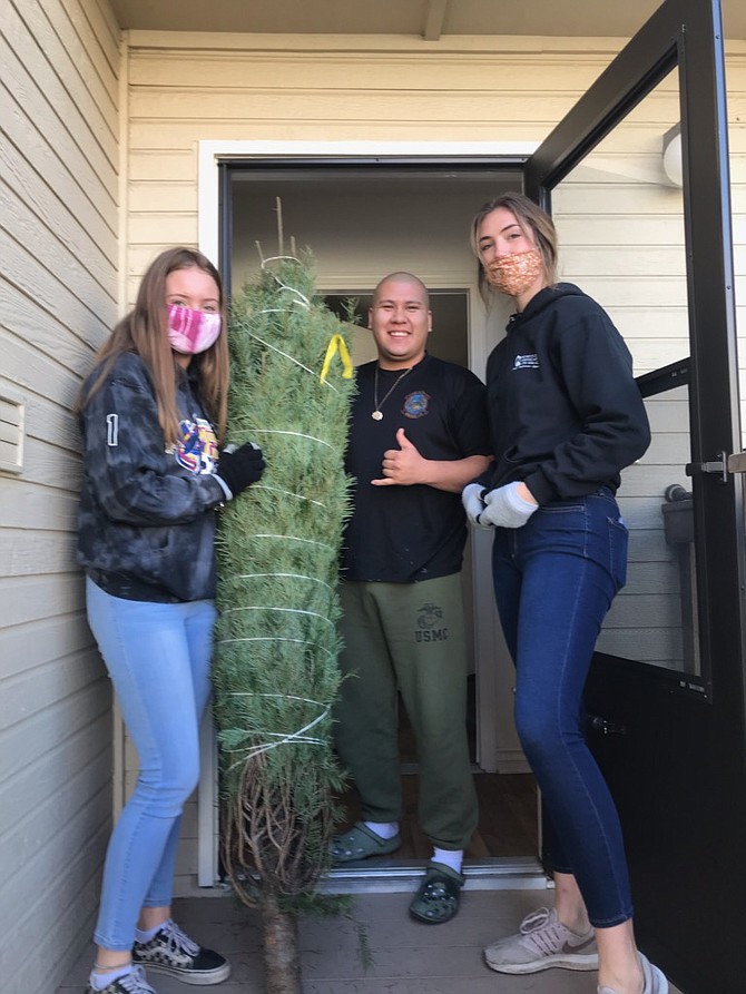 Sierra Lutheran High School students Kaitlyn Plummer, left, and Emma Riley deliver a tree to one of the servicemen based at the Mountain Warfare Training Center in Coleville.