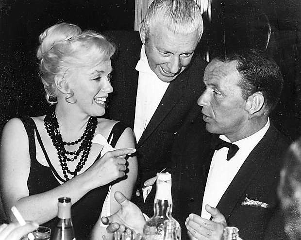 In this photo taken in 1959, Marilyn Monroe talks with Frank Sinatra while an unidentified man looks on at the Cal Neva Resort in Crystal Bay.