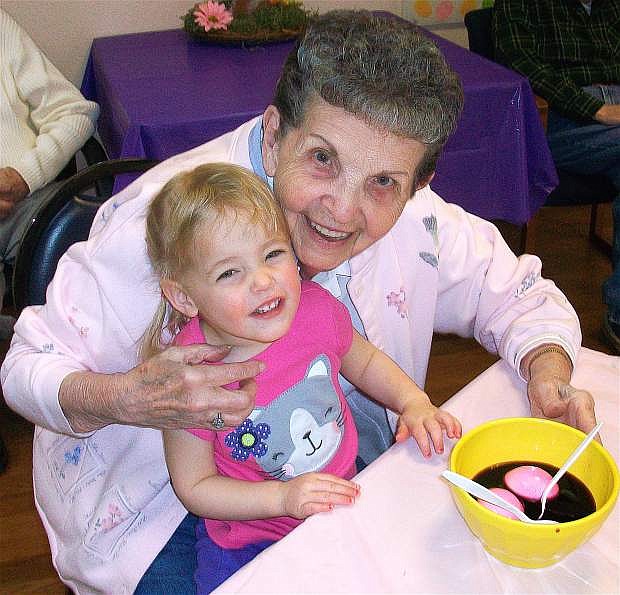A senior woman helps a young girl decorate Easter eggs at The Continuum. The interaction between seniors in the ReGenerations Adult Day Camp and children inthe day care center benefits both generations.