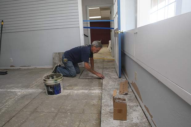 Mike Neally places new floor tile inside the Carson City Chamber of Commerce office.