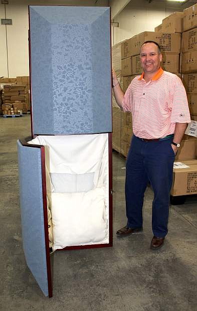 Chris Fleiner of Complemar West shows one of the cloth-covered caskets handled by the distribution firm.