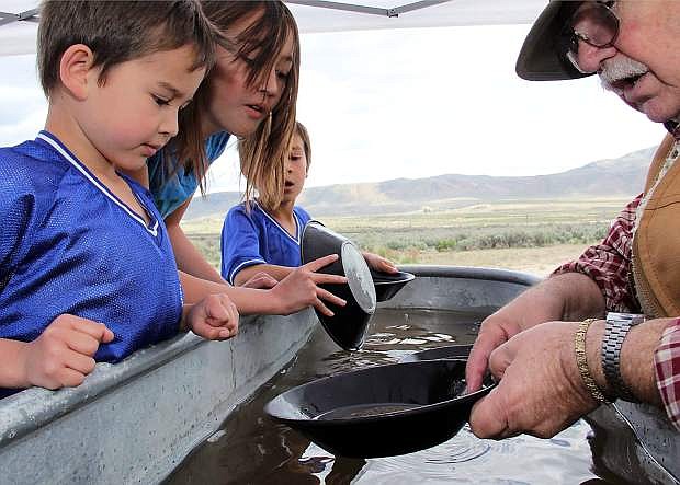 Don Lemons, resident gold panner, shows 5-year-old Henry Weight how to pan for gold as big sister Hannah and brother Austin look on. Lemons was on hand at the 2013 California Trail Days as an exhibitor teaching visitors about life along the Emigrant Trail.