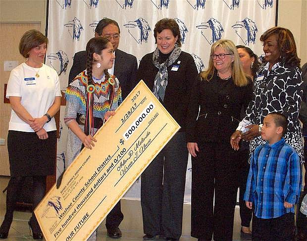 Natalia Chacon, a member of the Reno-Sparks Indian Colony, presents a revenue-sharing check from the Colony to representatives of the Washoe County School District, including, from left, Trustee Melina Raymond, RSIC Chairman Arlan Melendez, Trustee Veronica Frenkel, Trustee Katy Simon Holland, and Board of Trustees President Angela Taylor, Ph.D., as Keyi TwoHearts, front right, looks on.