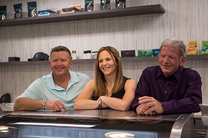 The owners of Greenleaf, Steve Duque, left, his sister Tammy Kolvet, and their father Spike Duque stand behind the counter of the cannabis dispensary.