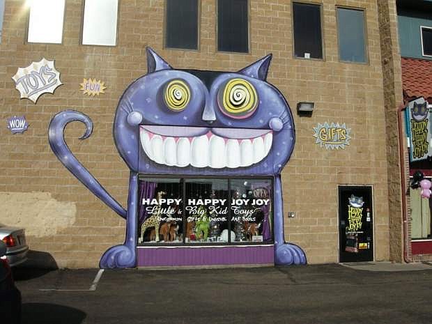 This smiling purple cat, painted by Midtown muralist Joe C. Rock, welcomes customers to Happy Happy Joy Joy toy store.