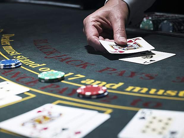 Male croupier holding card at Blackjack table, close-up