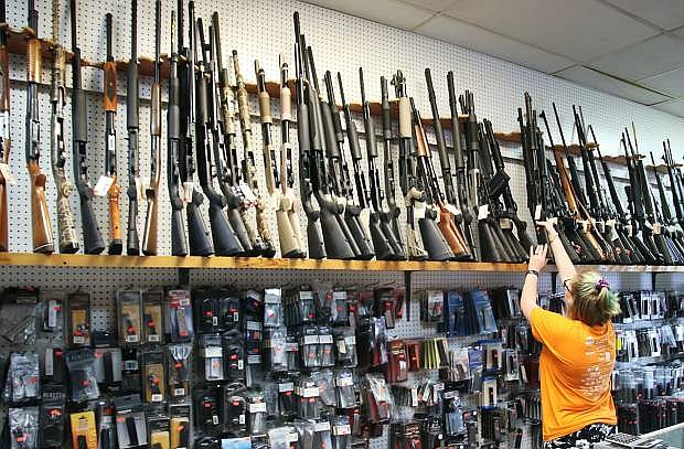 An employee of Bizarre Guns pulls down a shotgun from one of the store&#039;s rows of firearms. Greg Golden opened Bizarre Guns in 1997.