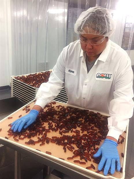 Alyson spreads newly made flax oil gel caps over drying trays at the NOW Foods manufacturing and distribution center in Sparks.