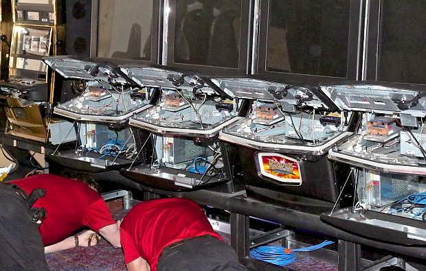 Workers put the finishing touches on a few of the 320 slot machines at Slotworld Friday.