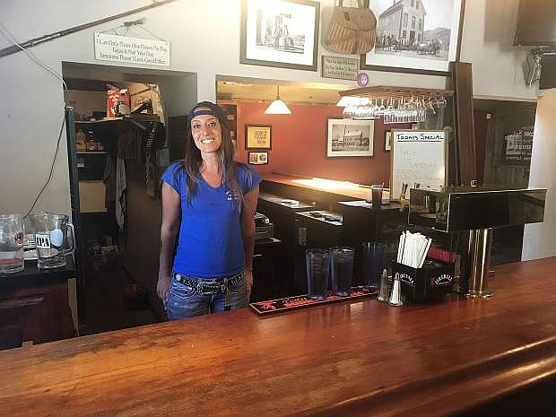 The new owner of the Cutthroat Saloon, Fawna Demond, behind the historical bar.