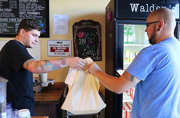 Walden&#039;s Coffeehouse barista JP Preston hands over a delivery order to an Uber Eats driver.