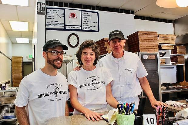 Judy and Walter Gloshinski (center, right) pose for a photo with employee Josh at Smiling With Hope Pizza.