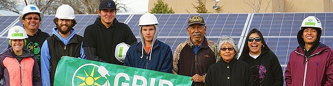 Members of the Tesuque Pueblo Tribe in New Mexico stand in front of a completed solar system installed by GRID Alternatives. 
