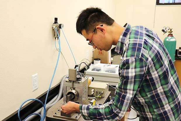 Xing Zhang, a Ph.D. student in mechanical engineering at UNR, uses the ultrasonic welder inside the college of engineering&#039;s advanced manufacturing lab.