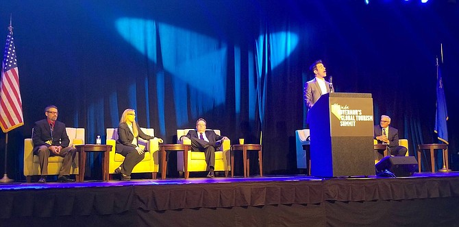 Jeff Civillico (standing) kicks off day two of the Nevada Governor&#039;s Global Tourism Summit on Tuesday, Nov. 13. Seated, left to right, are Nevada Department of Tourism Interim Director David Peterson, Reno Mayor Hillary Schieve, RSCVA  CEO Phil DeLone, and Rick Murdock, VP of Government Affairs at The Row.