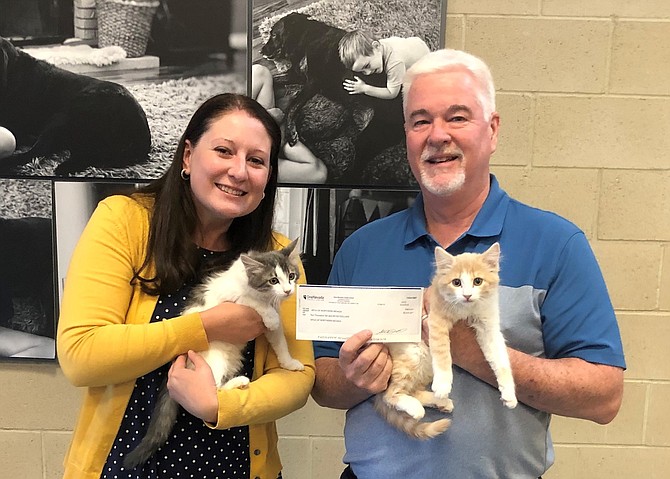 Lisa Jansen, of One Nevada Credit Union, and Sean Farnan, SPCA of Northern Nevada Development Director, hold two kittens up for adoption, along with the donation check.