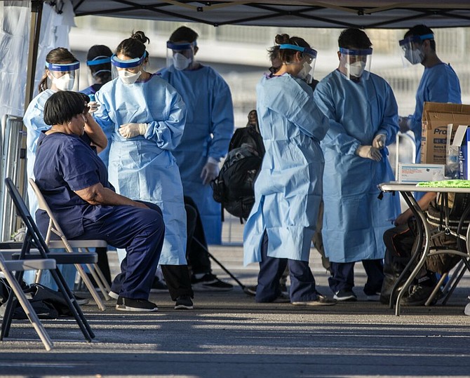 Medical personnel checks the temperature of a woman at the  temporary homeless shelter built in the parking lot at Cashman Center on Monday, March 30, 2020. The shelter was set up after Catholic Charities of Southern Nevada temporarily closed its night shelter because a man was tested positive for COVID-19.  (Jeff Scheid/The Nevada Independent)
